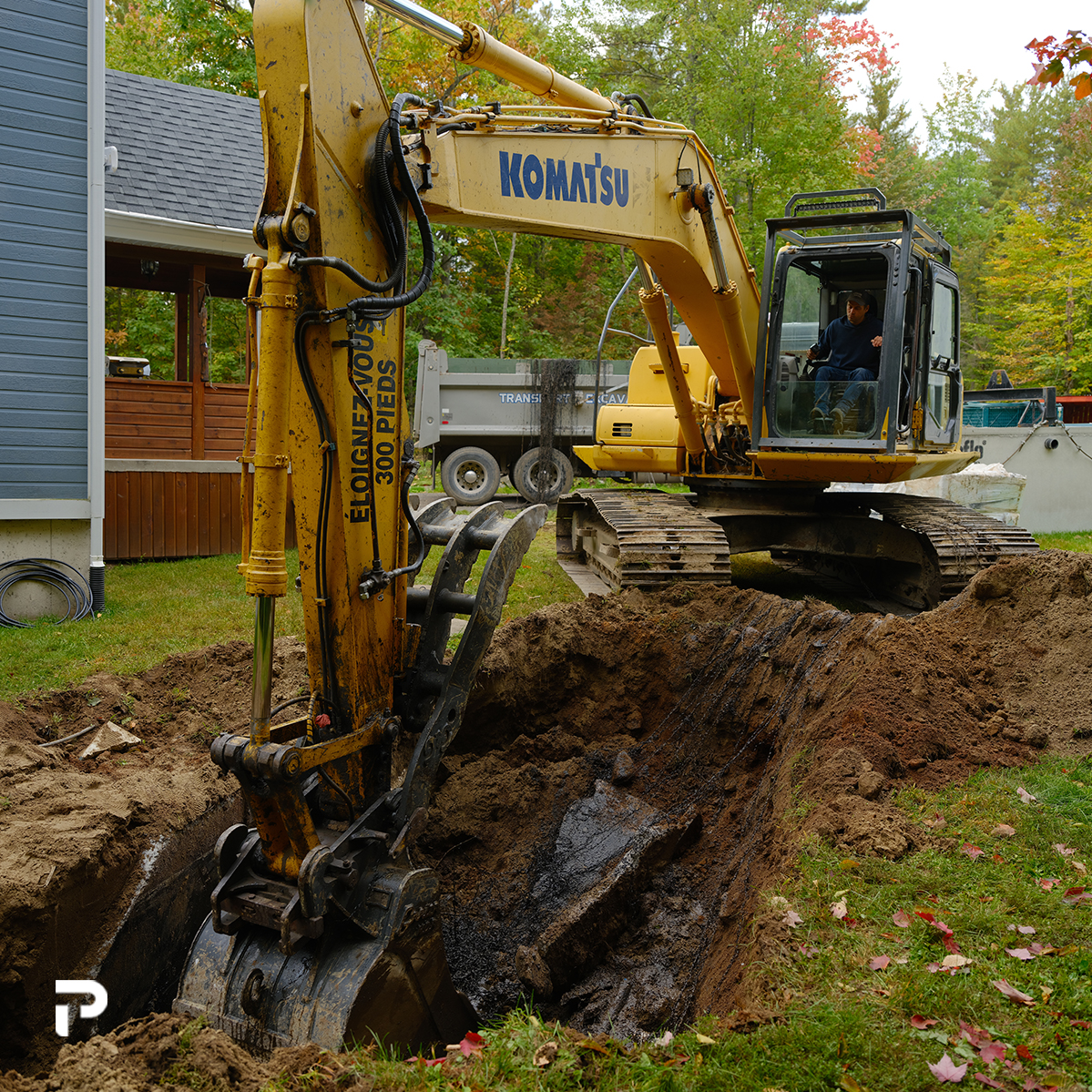 Excavateur creusant dans la terre pour retirer un système septique.