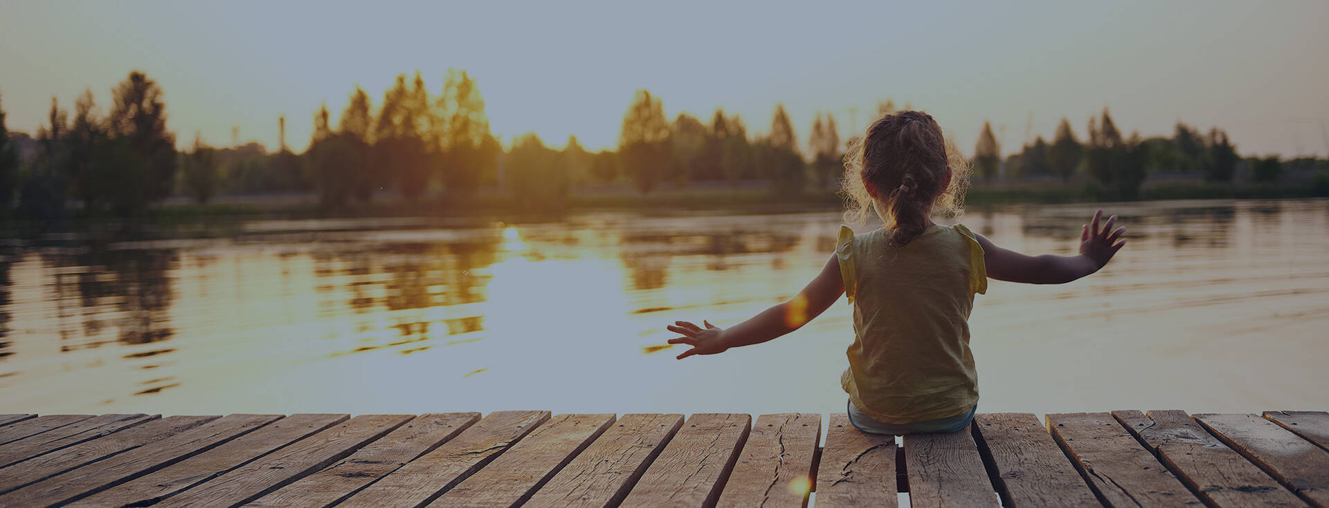 Girl sitting on a dock near a lake.