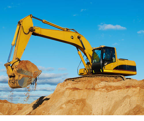 Large yellow excavator scooping sand out of a pit.