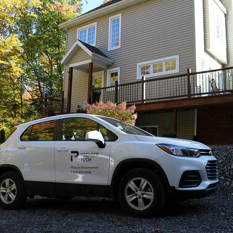 Premier Tech car in front of a house for septic system maintenance.