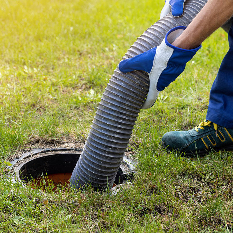 Technicien effectuant la vidange d'une fosse septique.